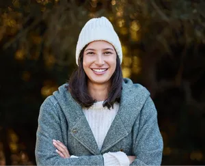 Smiling woman in a knitted beanie outdoors, used as a background removal sample